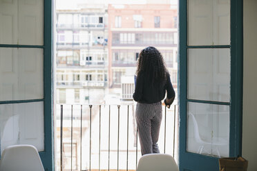 Young woman standing on balcony, looking at view - EBSF001449