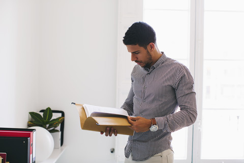 Junger Mann im Büro liest Akten, lizenzfreies Stockfoto