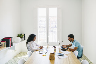 Young businessman and woman working together in office, using laptop - EBSF001487