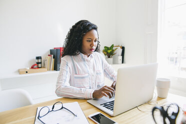 Junge Frau arbeitet im Büro und benutzt einen Laptop - EBSF001488