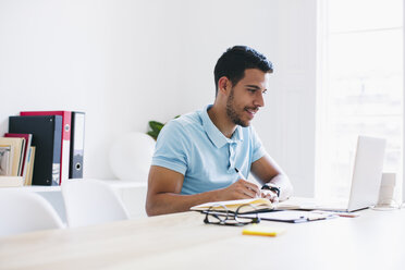 Junger Mann arbeitet im Büro und benutzt einen Laptop - EBSF001490