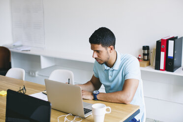 Young man working in office, using laptop - EBSF001491