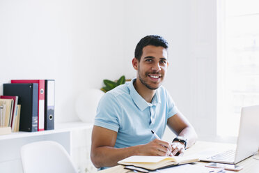 Junger Mann arbeitet im Büro und benutzt einen Laptop - EBSF001510