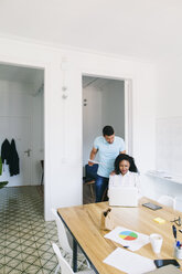 Young businessman and woman working together in office, using laptop - EBSF001517