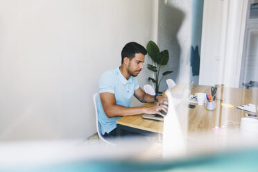 Junger Mann arbeitet im Büro und benutzt einen Laptop - EBSF001528