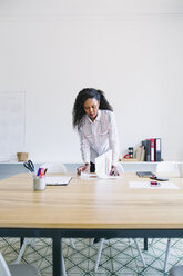 Young businesswoman standing at desk looking trough files - EBSF001541