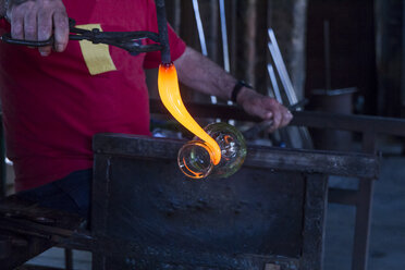 Mann bei der Arbeit mit geschmolzenem Glas in einer Glasfabrik - ABZF000680