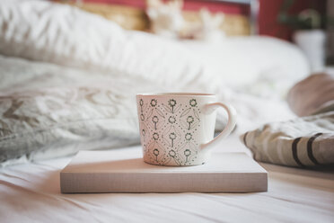 Buch und Tasse Kaffee auf einem Bett - ASCF000620