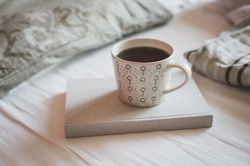 Buch und eine Tasse schwarzer Kaffee auf einem Bett - ASCF000621