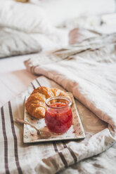 Teller mit Croissant und Glas Erdbeermarmelade auf dem Bett - ASCF000622