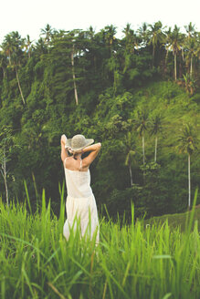 Indonesien, Bali, Rückenansicht einer Frau in Sommerkleid und Hut in der Natur - KNTF000338