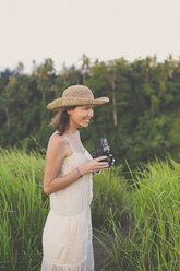 Lächelnde Frau mit Retro-Kamera in der Natur - KNTF000341