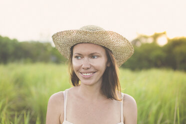 Portrait of smiling woman wearing summer hat in nature - KNTF000345