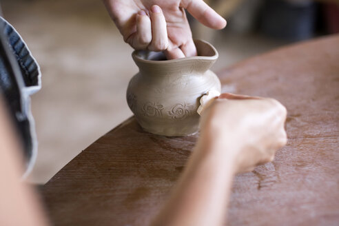 Potter in workshop working on earthenware jar - KNTF000359