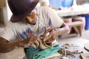 Potter in workshop working on earthenware jar - KNTF000373