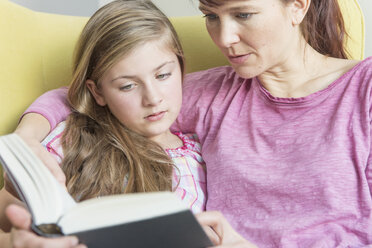 Mother and daughter reading a book together - NHF001510