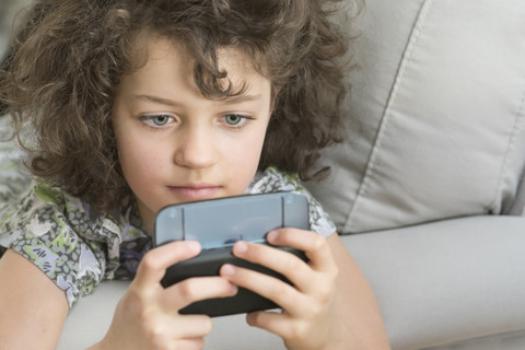 Mädchen spielt mit mobilem Gerät, lizenzfreies Stockfoto