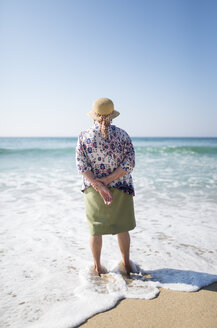 Back view of senior woman standing on the beach - RAEF001221