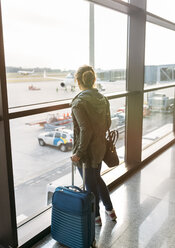 Spanien, Asturien, Frau wartet mit ihrem Koffer auf das Boarding im Flughafen - MGOF001949