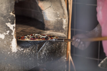 Man putting pizza in pizza oven - ZEF008718