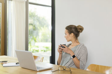 Frau am Tisch mit einer Tasse Kaffee und einem Laptop - SBOF000060