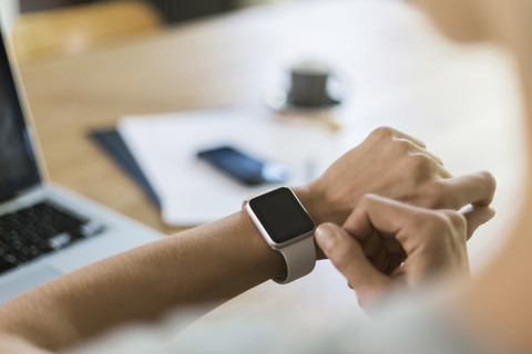 Frau schaut auf Smartwatch, lizenzfreies Stockfoto