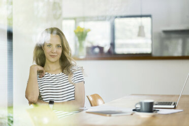 Portrait of confident woman with laptop at table - SBOF000075