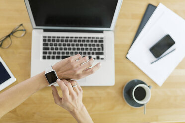 Woman with smartwatch and laptop at desk - SBOF000081
