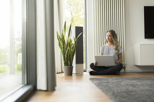 Frau zu Hause auf dem Boden sitzend mit Laptop - SBOF000087