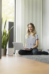 Frau zu Hause auf dem Boden sitzend mit Laptop - SBOF000089