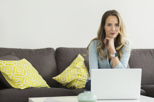 Frau zu Hause auf der Couch sitzend mit Laptop - SBOF000094