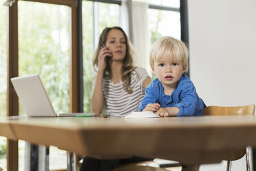 Mutter mit Laptop und Mobiltelefon und Sohn im Vordergrund - SBOF000106