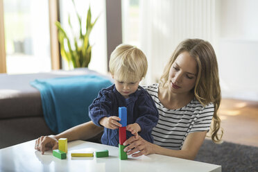 Mother and son stacking building bricks in living room - SBOF000117