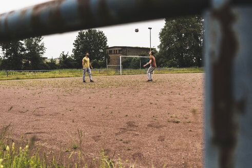 Zwei Männer spielen Fußball auf einem Aschenplatz - UUF007687