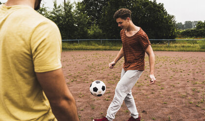 Zwei Männer spielen Fußball auf einem Aschenplatz - UUF007688