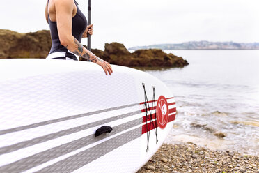 Frau mit Stand Up Paddle Board an der Küste - MGOF001952