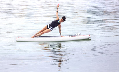 Woman practicing paddle board yoga - MGOF001957