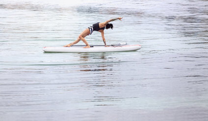 Woman practicing paddle board yoga - MGOF001958