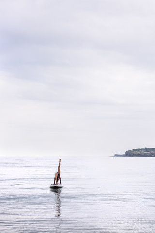 Frau übt Yoga auf dem Paddelbrett, lizenzfreies Stockfoto