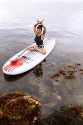 Woman practicing paddle board yoga - MGOF001962