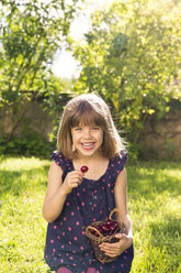 Porträt eines lachenden kleinen Mädchens, das im Garten Kirschen isst - LVF004964
