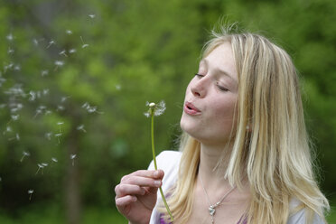 Portrait of blond young woman blowing blowball - LBF001435
