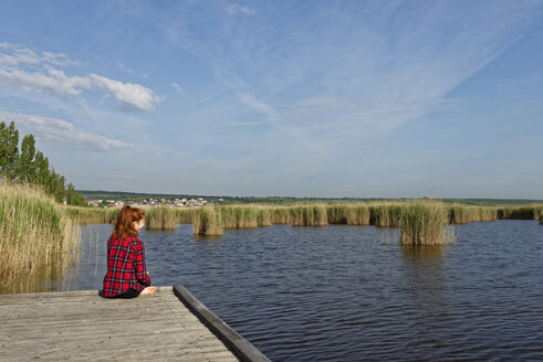 Österreich, Burgenland, Neusiedler See, Mörbisch, junges Mädchen sitzt auf Steg - LBF001436