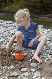 Blondes kleines Mädchen spielt mit Sand am Flussufer - TCF005002