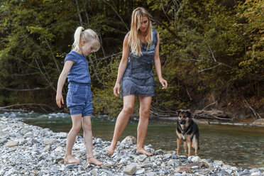 Mutter und ihre kleine Tochter zusammen mit ihrem Hund am Flussufer - TCF005003