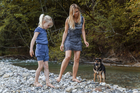 Mother and her little daughter together with their dog at riverside - TCF005003