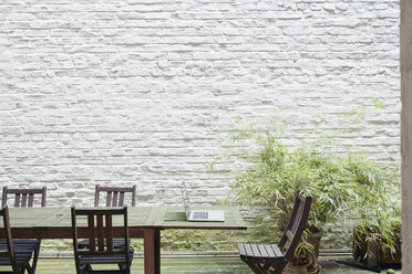 Opened laptop standing on a table in a backyard - RHF001597