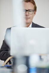 Portrait of businessman working with laptop - RHF001607