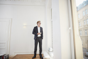 Businessman in the office looking through window - RHF001608