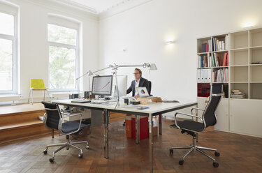 Geschäftsmann sitzt am Schreibtisch in einem Büro und arbeitet mit einem Computer - RHF001617